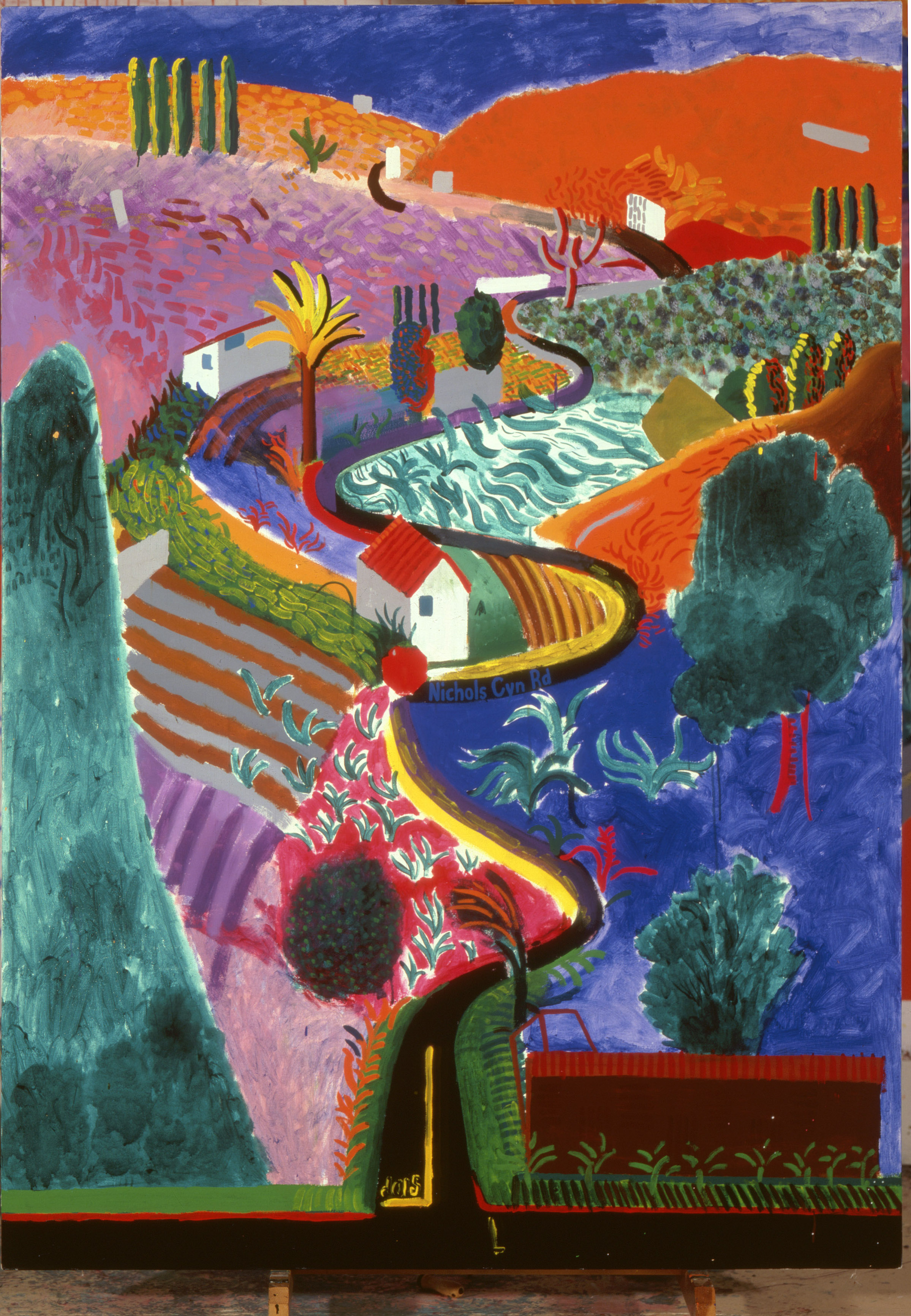 A landscape painting by David Hockney. It depicts a road winding into the distance through brightly colored hills and fields.